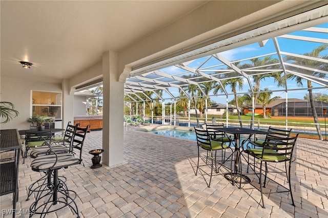 view of patio featuring glass enclosure and a swimming pool with hot tub