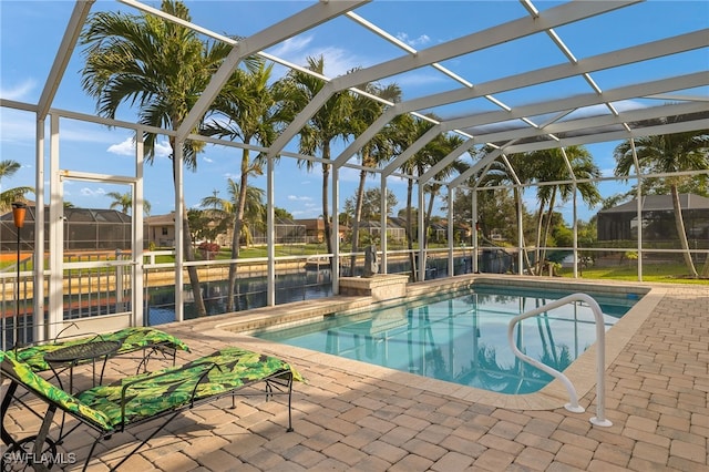 view of pool with glass enclosure, a water view, and a patio