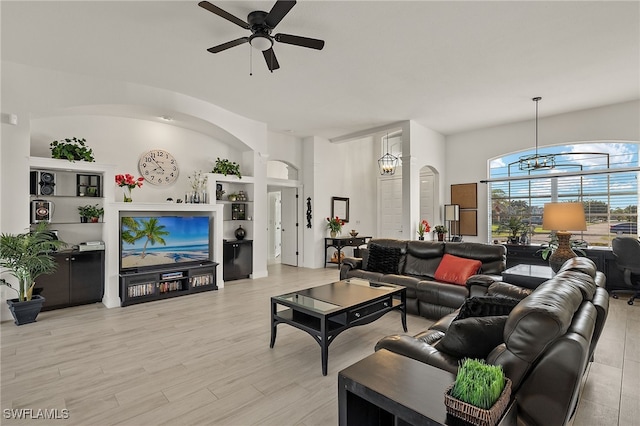 living room featuring ceiling fan with notable chandelier and light wood-type flooring