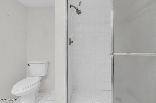 bathroom with tile patterned floors, toilet, and a shower with shower door