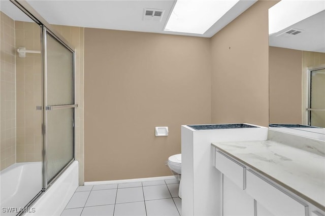 full bathroom featuring tile patterned floors, toilet, bath / shower combo with glass door, a skylight, and vanity