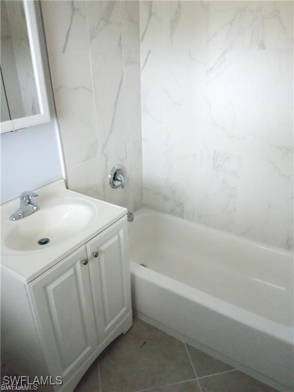 bathroom with tile patterned floors, vanity, and  shower combination