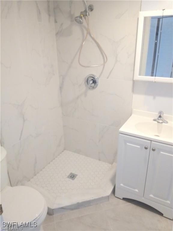 bathroom with toilet, vanity, and tiled shower