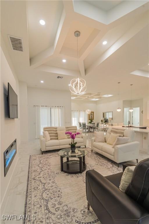 living room featuring coffered ceiling and a notable chandelier