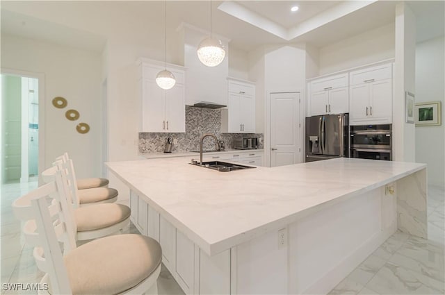 kitchen with tasteful backsplash, stainless steel appliances, pendant lighting, white cabinets, and a breakfast bar area