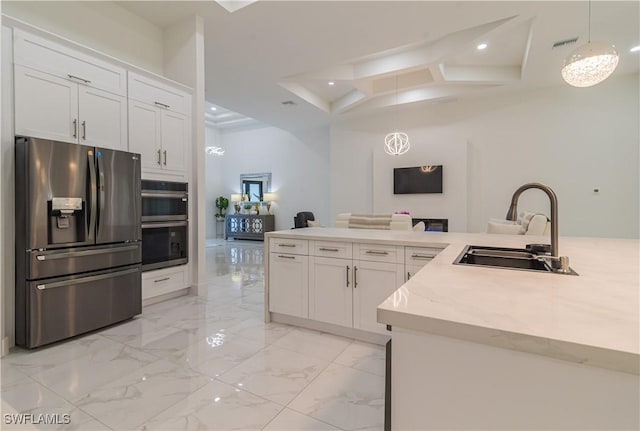 kitchen with light stone countertops, stainless steel appliances, sink, white cabinets, and hanging light fixtures