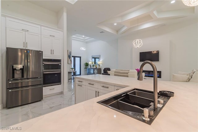 kitchen featuring appliances with stainless steel finishes, light stone counters, sink, decorative light fixtures, and white cabinets