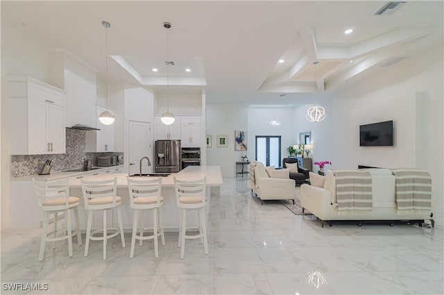 kitchen featuring white cabinetry, sink, hanging light fixtures, stainless steel refrigerator with ice dispenser, and a breakfast bar area