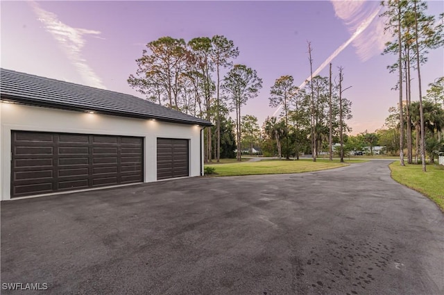 garage at dusk featuring a yard