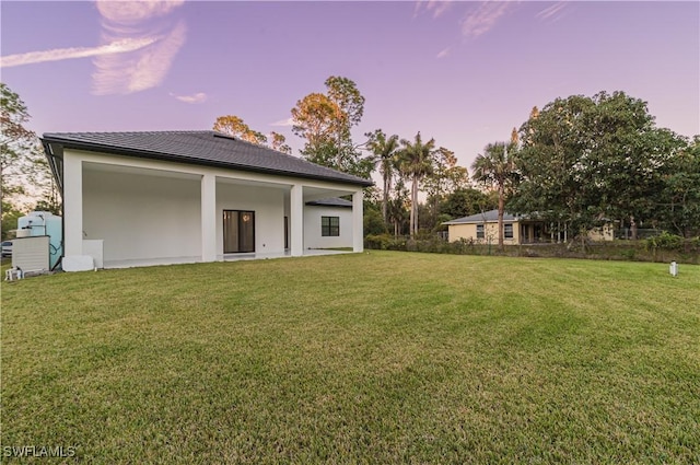 back house at dusk featuring a yard