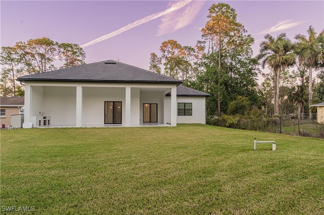 back house at dusk with a lawn