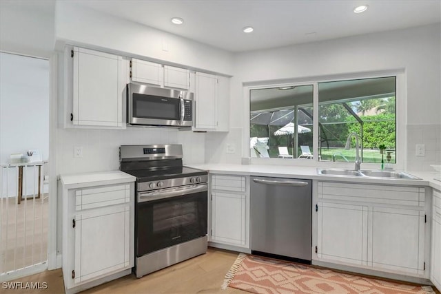 kitchen featuring light countertops, a sink, appliances with stainless steel finishes, and light wood-type flooring