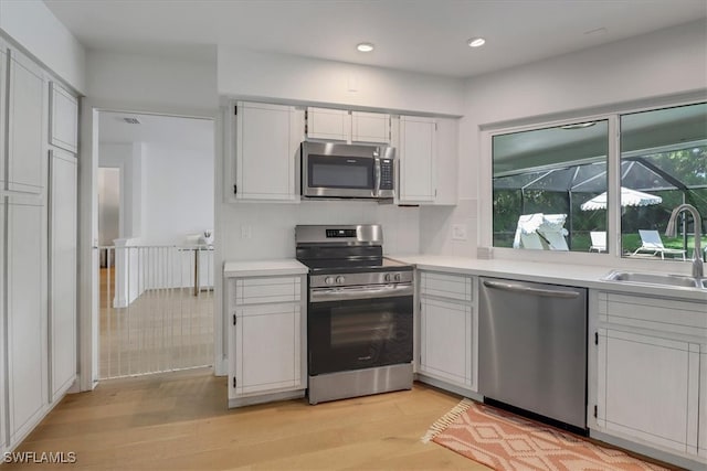 kitchen with light wood-style flooring, a sink, stainless steel appliances, and light countertops