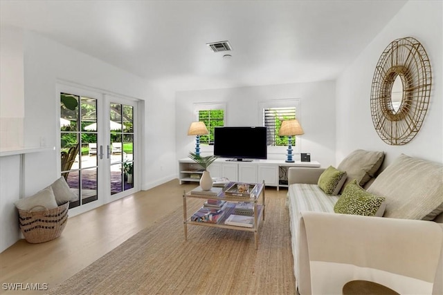 living room featuring baseboards, visible vents, french doors, and light wood finished floors