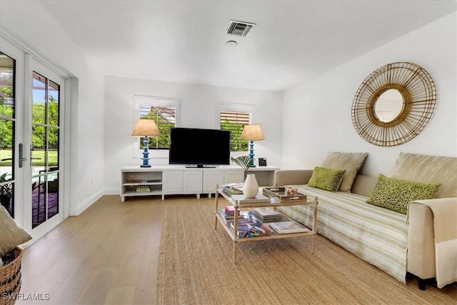 living room with baseboards, visible vents, and wood finished floors