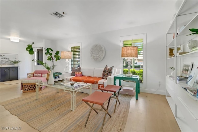 living room featuring baseboards, visible vents, and wood finished floors