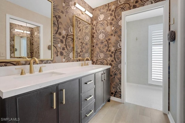 full bathroom featuring a sink, double vanity, and wallpapered walls