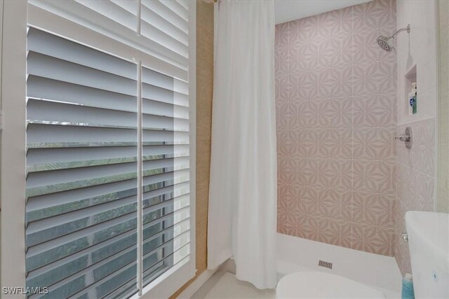 bathroom featuring toilet and tiled shower