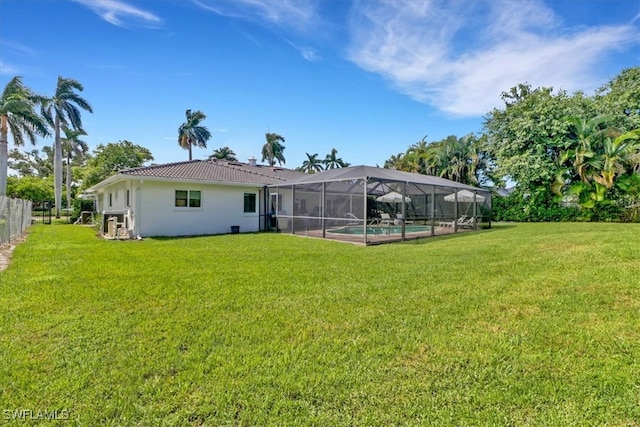 rear view of property with glass enclosure, a tile roof, stucco siding, a lawn, and an outdoor pool