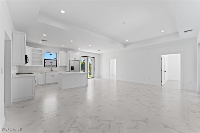 kitchen featuring a center island, a raised ceiling, sink, white cabinets, and white fridge with ice dispenser