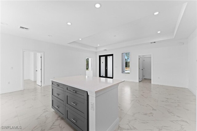 kitchen with gray cabinets, a center island, a raised ceiling, and french doors