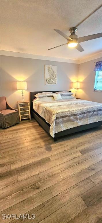 bedroom featuring ceiling fan, light hardwood / wood-style floors, and a textured ceiling