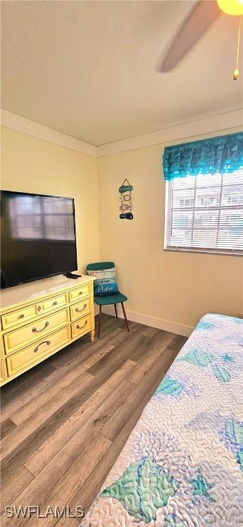 bedroom with ceiling fan, dark wood-type flooring, and ornamental molding