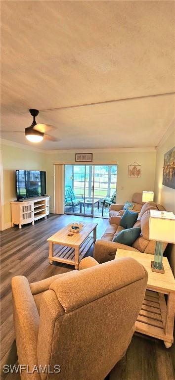 living room with dark hardwood / wood-style flooring, ceiling fan, and crown molding