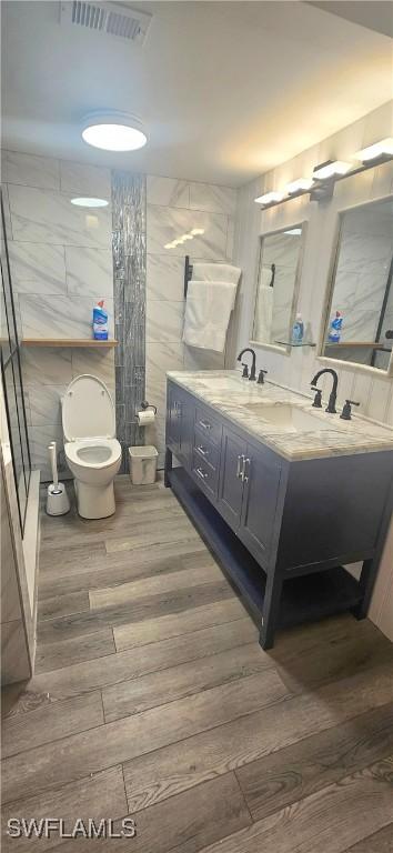 bathroom with vanity, toilet, wood-type flooring, and tile walls