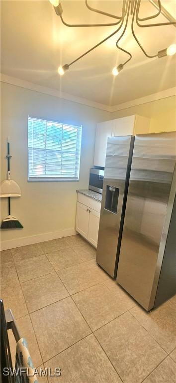 kitchen featuring crown molding, white cabinetry, stainless steel appliances, and light tile patterned floors