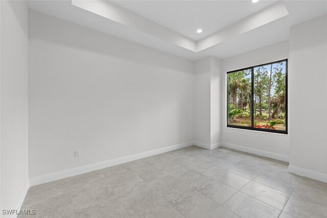 tiled spare room with a tray ceiling