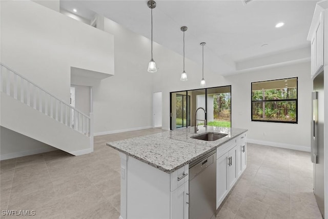 kitchen with light stone counters, a kitchen island with sink, sink, dishwasher, and white cabinetry