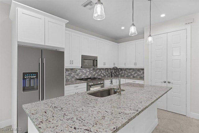 kitchen featuring sink, stainless steel appliances, an island with sink, decorative light fixtures, and white cabinets