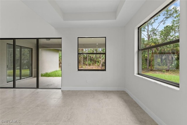 spare room with light tile patterned flooring and a tray ceiling