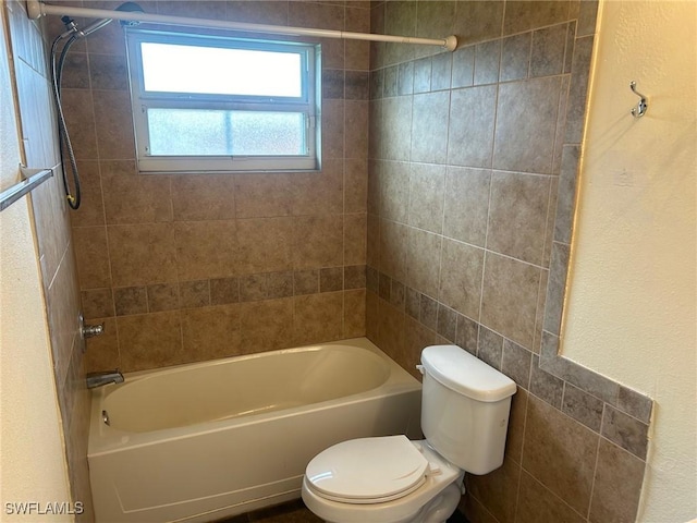 bathroom featuring tiled shower / bath combo and toilet