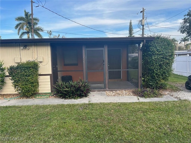 rear view of property with a sunroom and a yard