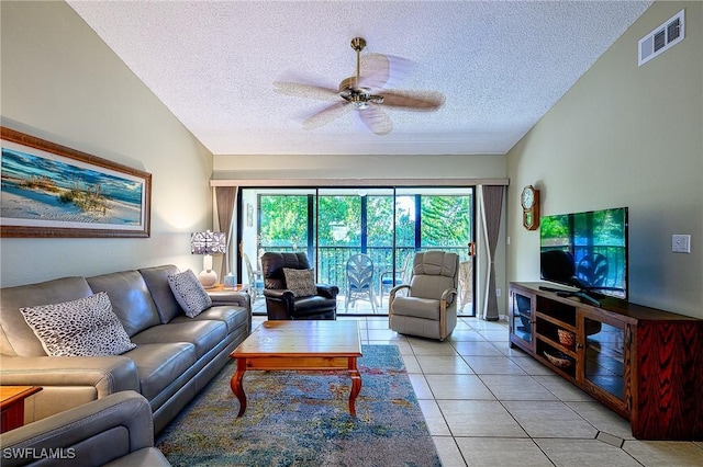 living room featuring ceiling fan, light tile patterned flooring, and a textured ceiling