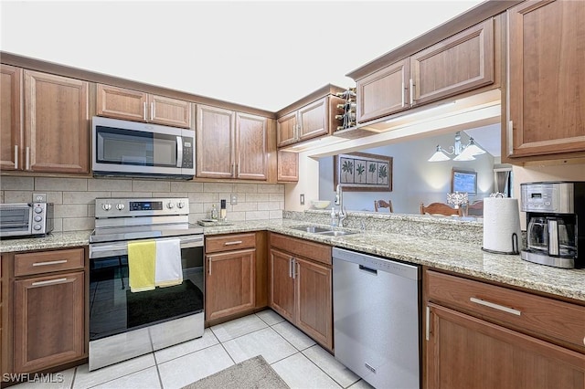 kitchen featuring sink, tasteful backsplash, light tile patterned flooring, light stone counters, and stainless steel appliances