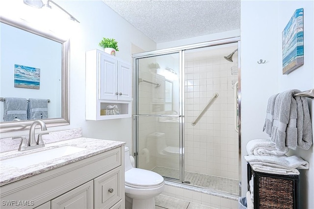 bathroom featuring vanity, a textured ceiling, a shower with door, tile patterned flooring, and toilet