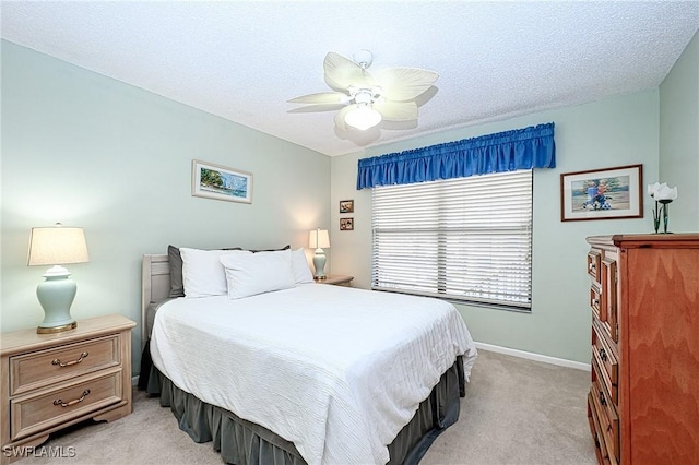 carpeted bedroom featuring ceiling fan and a textured ceiling