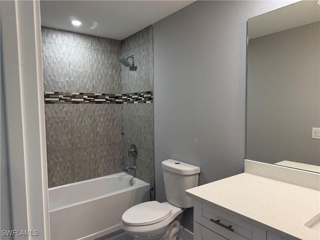 full bathroom featuring toilet, tiled shower / bath, and vanity