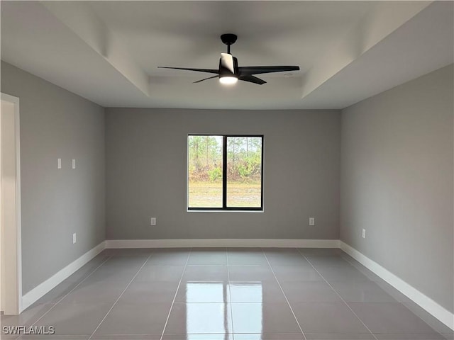 spare room featuring ceiling fan, light tile patterned floors, and a raised ceiling