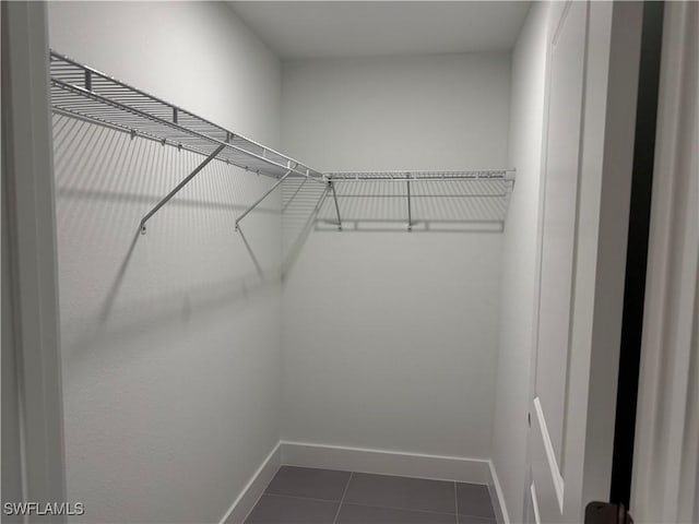 walk in closet featuring dark tile patterned flooring