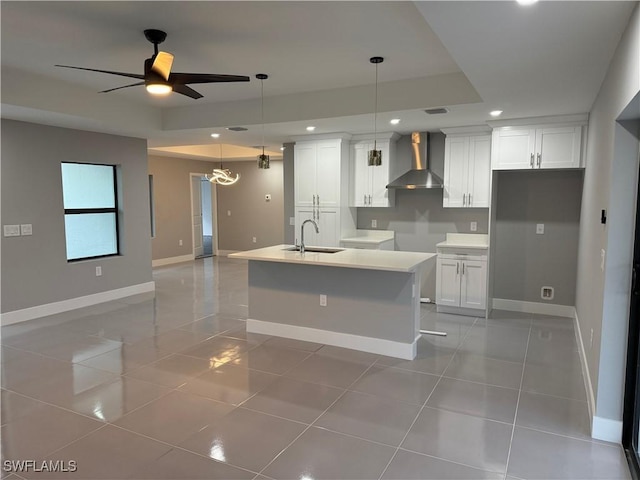 kitchen featuring white cabinets, wall chimney range hood, an island with sink, sink, and light tile patterned flooring