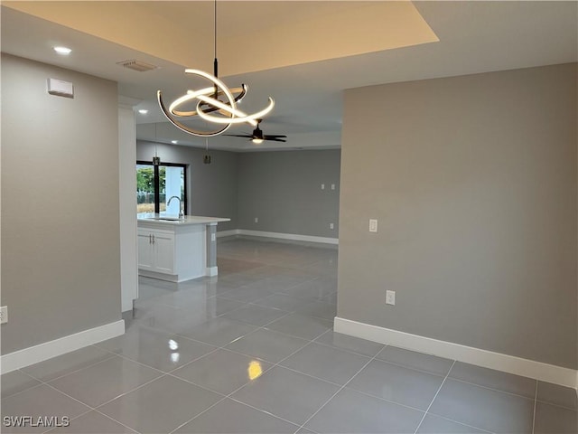 tiled spare room featuring sink and ceiling fan with notable chandelier