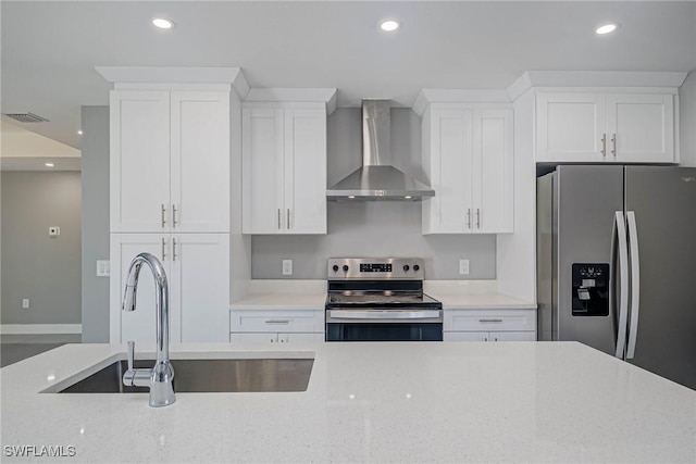 kitchen featuring wall chimney exhaust hood, sink, white cabinetry, appliances with stainless steel finishes, and light stone countertops