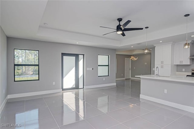 kitchen with decorative light fixtures, white cabinets, and a tray ceiling