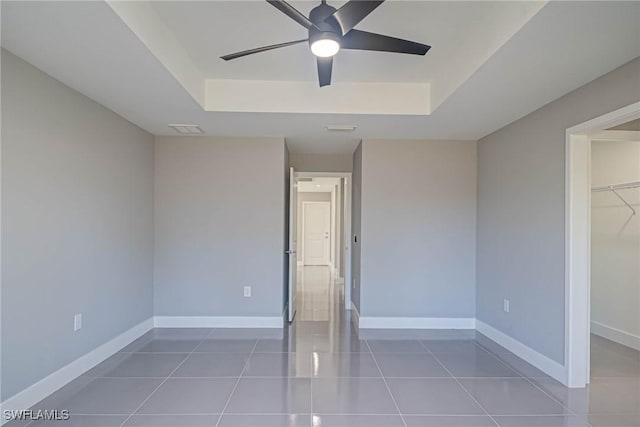 unfurnished bedroom featuring tile patterned flooring, a raised ceiling, and ceiling fan