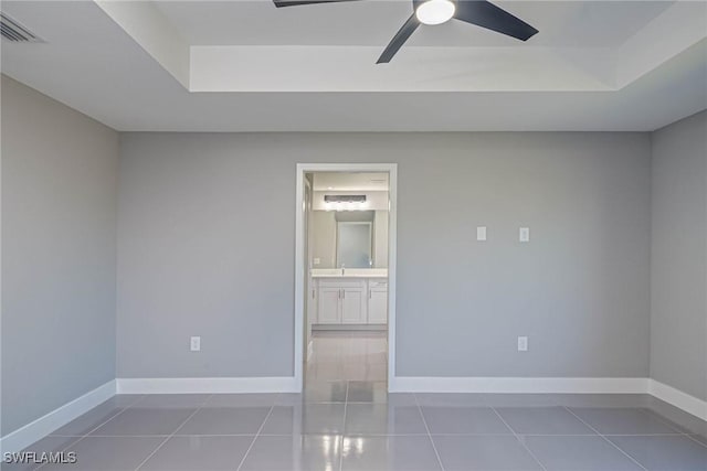 spare room with tile patterned flooring, sink, a raised ceiling, and ceiling fan