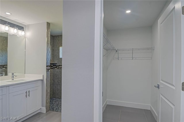 bathroom featuring tile patterned flooring, vanity, and a tile shower